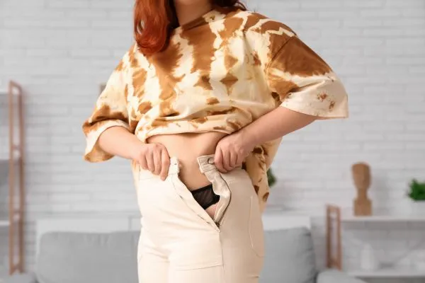 Image of woman trying to do her trousers up after pregnancy weight gain Sunningdale