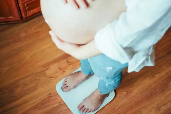 Image of woman weighing herself and experiencing weight gain through pregnancy Sunningdale